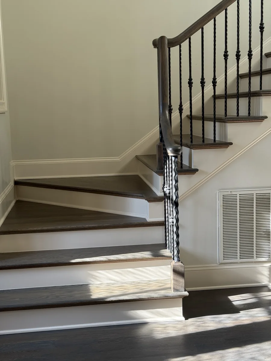Dark stained treads with white risers and wrought iron balusters, installed in a Charlotte home
